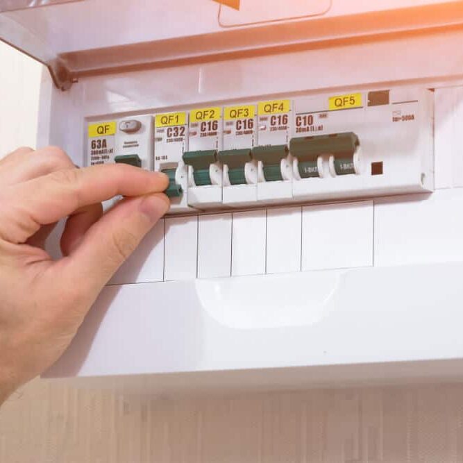 Professional Hot Shot Electric certified electrician repairing breaker box with screwdriver – licensed Tulsa experts fix tripped breakers and upgrade panels for safe, reliable home power in Oklahoma.