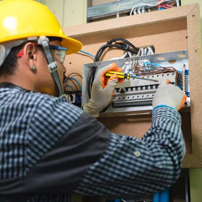 Professional Hot Shot Electric certified electrician repairing breaker box with screwdriver – licensed Tulsa experts fix tripped breakers and upgrade panels for safe, reliable home power in Oklahoma.