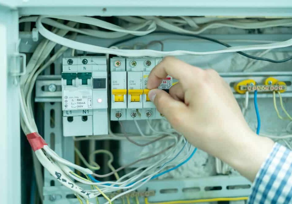 Professional Hot Shot Electric certified electrician repairing breaker box with screwdriver – licensed Tulsa experts fix tripped breakers and upgrade panels for safe, reliable home power in Oklahoma.