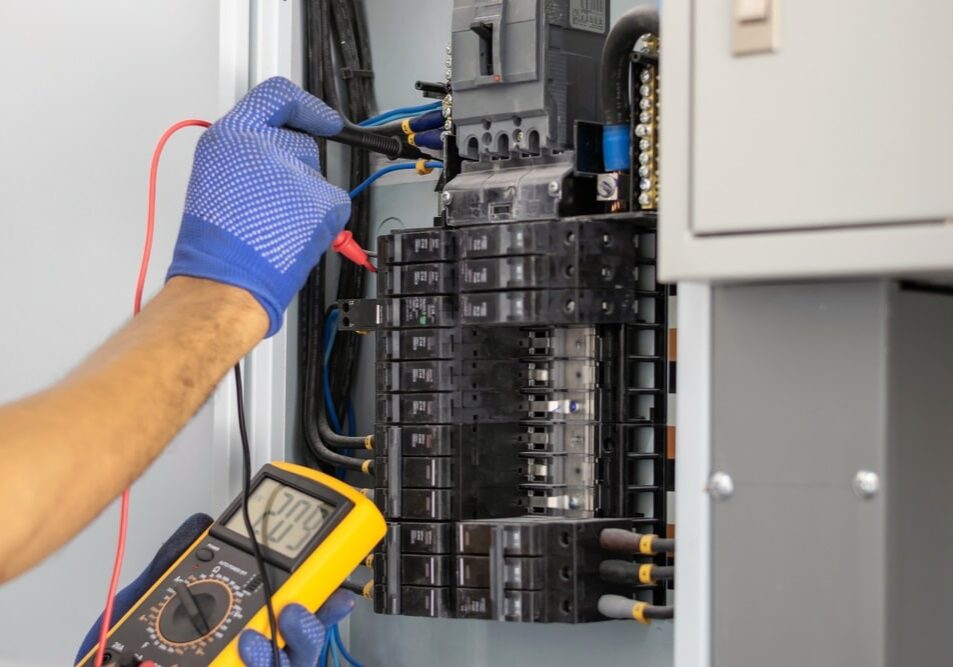 Professional Hot Shot Electric certified electrician testing breaker panel with multimeter – licensed Tulsa experts perform safe diagnostics and repairs for reliable home electrical systems in Oklahoma.