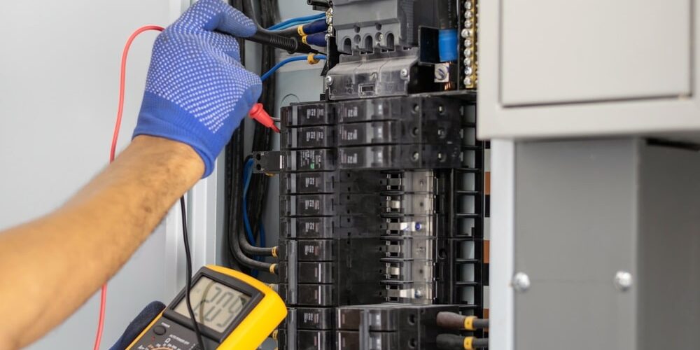 Professional Hot Shot Electric certified electrician repairing breaker box with screwdriver – licensed Tulsa experts fix tripped breakers and upgrade panels for safe, reliable home power in Oklahoma.